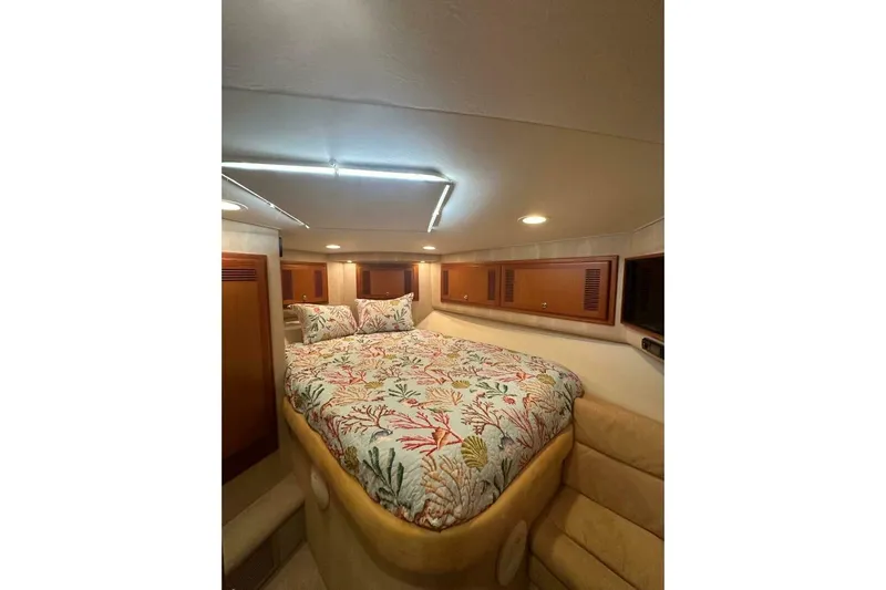 Merry Yacht Yacht Photos Pics 2004 Cabo 48 Flybridge cabin with floral bedding and wooden storage cabinets.