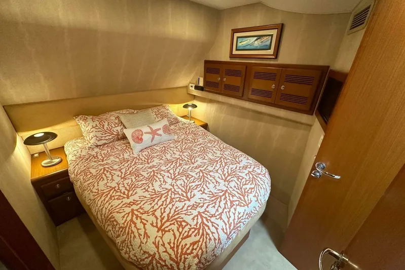 Merry Yacht Yacht Photos Pics 2004 Cabo 48 Flybridge cabin with coral-patterned bedding and wooden storage cabinets.