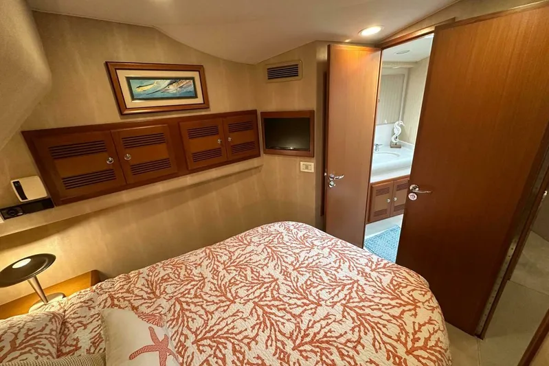 Merry Yacht Yacht Photos Pics 2004 Cabo 48 Flybridge cabin with cozy bed, wooden cabinets, and ensuite bathroom.