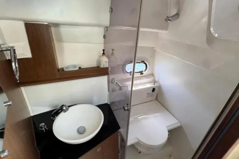  Yacht Photos Pics 2020 Jeanneau Leader 9.0 WA boat bathroom with sink, toilet, and porthole window.