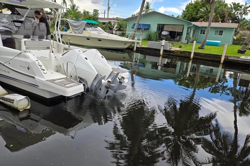  Yacht Photos Pics 2020 Jeanneau Leader 9.0 WA boat docked in a canal, reflecting palm trees and houses.