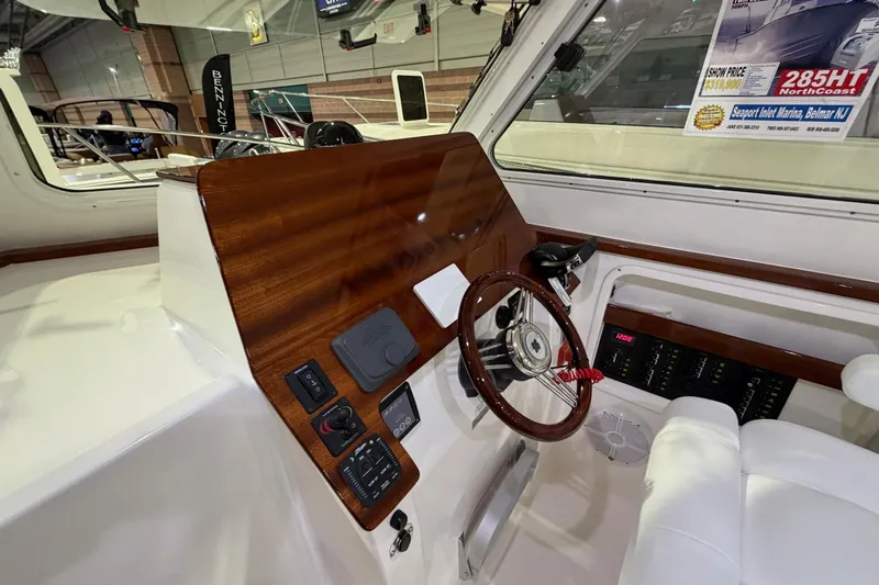  Yacht Photos Pics Interior view of 2026 NorthCoast 255 Cabin boat with wooden dashboard and steering wheel.