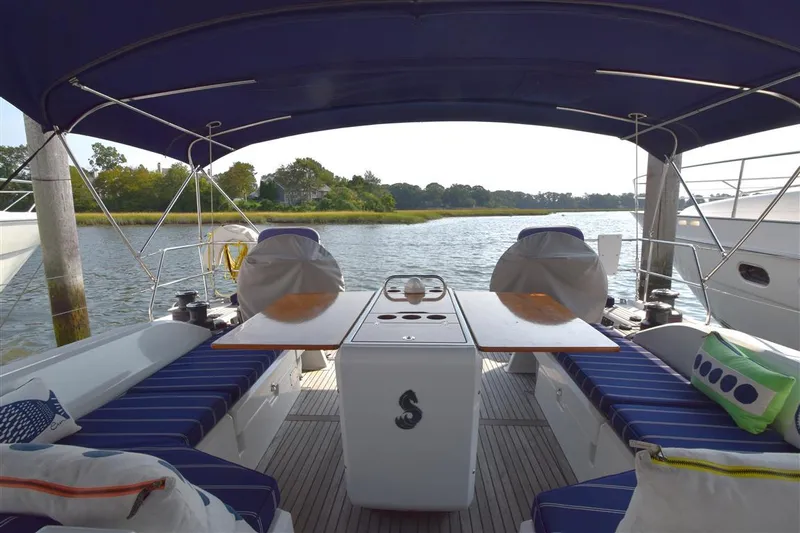  Yacht Photos Pics 2019 Beneteau 51.1 yacht cockpit with blue seating and table, docked by serene water.