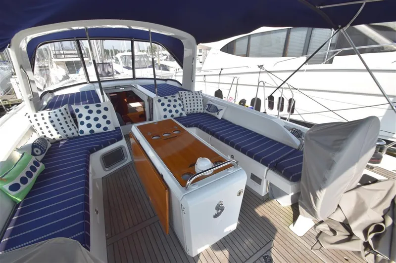  Yacht Photos Pics 2019 Beneteau 51.1 yacht cockpit with blue-striped seating and wooden table.