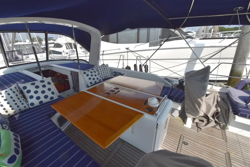  Yacht Photos Pics 2019 Beneteau 51.1 yacht cockpit with blue seating, wooden table, and polka dot cushions.