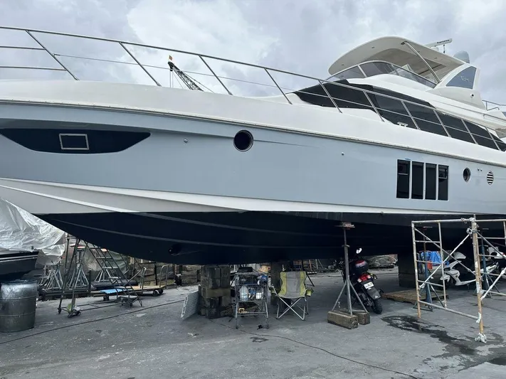  Yacht Photos Pics 2012 Azimut 64 yacht on dry dock, undergoing maintenance with scaffolding and equipment nearby.