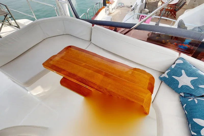 Vitamin Sea Yacht Photos Pics Cozy seating area on 2021 Beneteau Swift Trawler 35 with wooden table and starfish cushions.