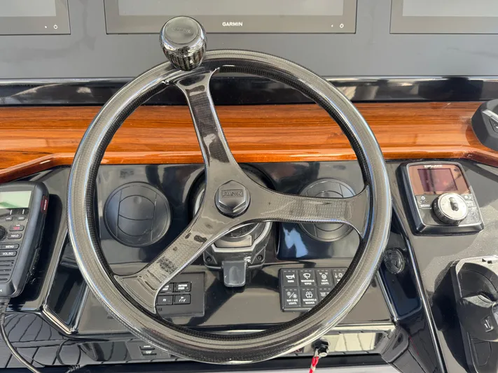  Yacht Photos Pics Steering wheel of 2022 Everglades 395cc boat with control panel and wood accents.