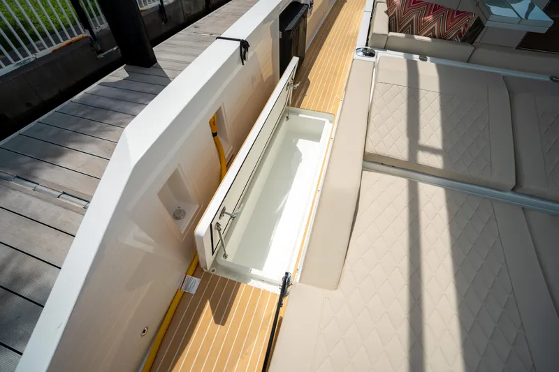  Yacht Photos Pics 2025 De Antonio Yachts D42 Open deck with storage compartment and cushioned seating.