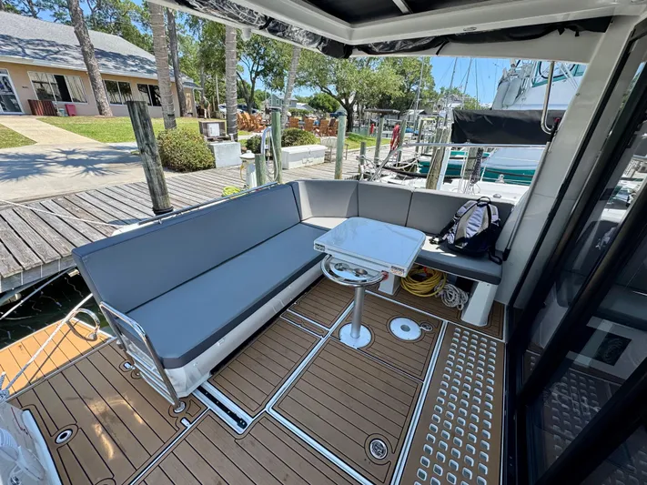 Yacht Photos Pics 2024 Beneteau Antares 11 boat deck with seating and table, docked at marina.