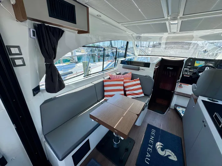  Yacht Photos Pics 2024 Beneteau Antares 11 interior with seating, table, and striped cushions.