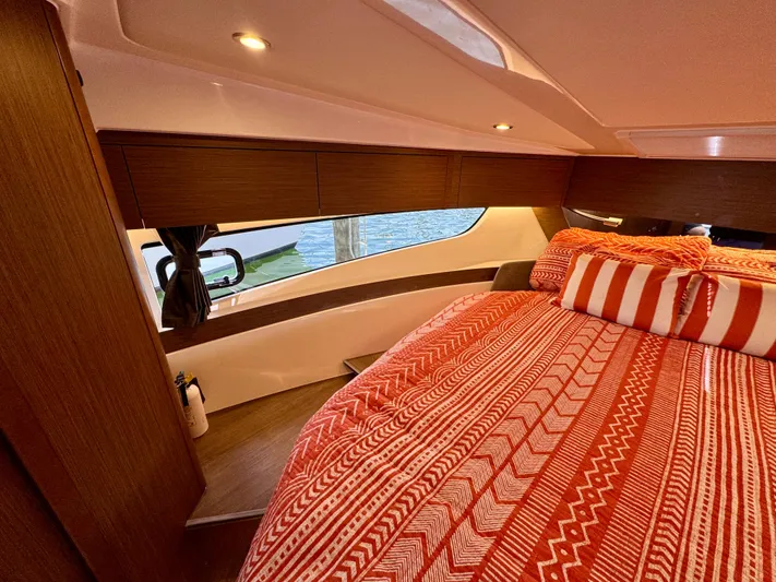  Yacht Photos Pics 2024 Beneteau Antares 11 cabin with red patterned bedding and modern wood finish.