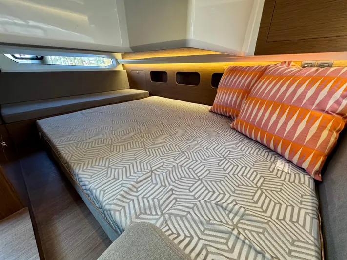 Yacht Photos Pics 2024 Beneteau Antares 11 cabin with geometric bedding and colorful pillows.