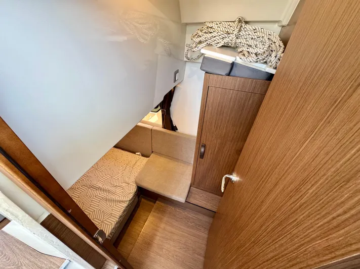  Yacht Photos Pics 2024 Beneteau Antares 11 cabin interior with wood finish and cozy bedding.