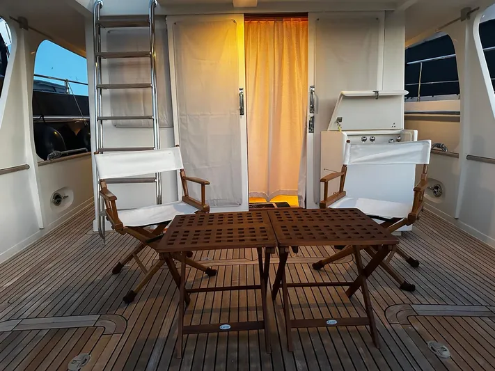 Smaragd Yacht Photos Pics Deck of 2003 Fleming 55 yacht with chairs and table, warm lighting.