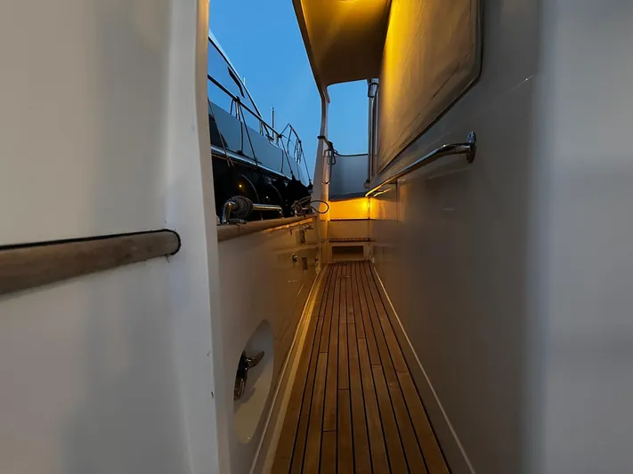 Smaragd Yacht Photos Pics Narrow walkway on a 2003 Fleming 55 yacht with wooden deck and ambient lighting.