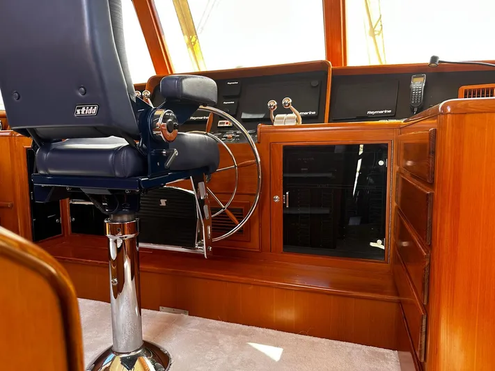 Smaragd Yacht Photos Pics Pilot seat and helm of a 2003 Fleming 55 yacht, featuring wooden cabinetry and navigation equipment.