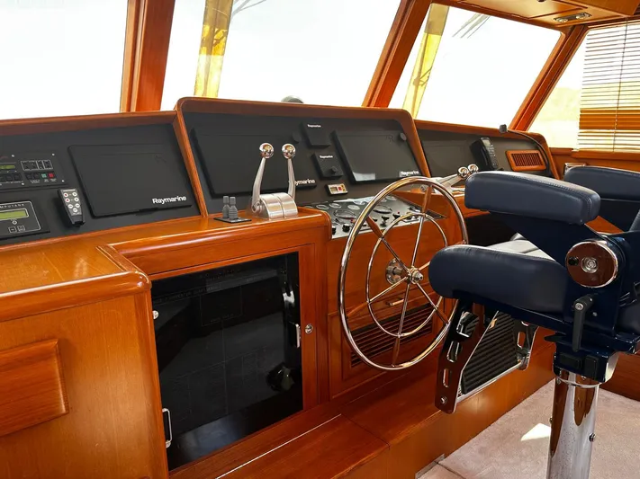 Smaragd Yacht Photos Pics Helm of 2003 Fleming 55 yacht with Raymarine navigation, wooden finish, and captain's chair.