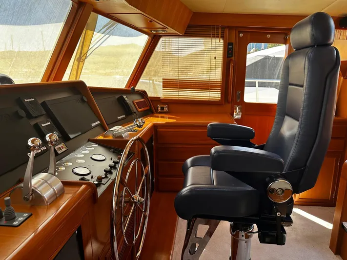 Smaragd Yacht Photos Pics Pilot seat and control panel of a 2003 Fleming 55 yacht, featuring wooden interior.
