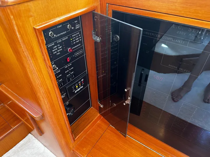 Smaragd Yacht Photos Pics Control panel of a 2003 Fleming 55 yacht with wooden finish and glass cover.