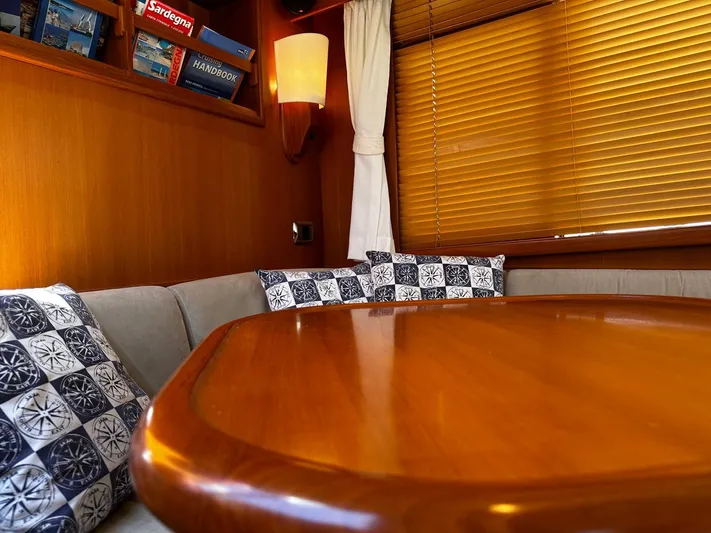 Smaragd Yacht Photos Pics Cozy interior of a 2003 Fleming 55 yacht with wooden table and nautical-themed cushions.