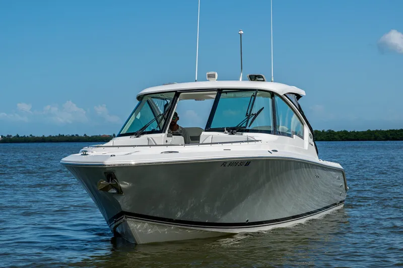  Yacht Photos Pics 2021 Pursuit DC 326 Dual Console boat cruising on calm waters under a clear blue sky.