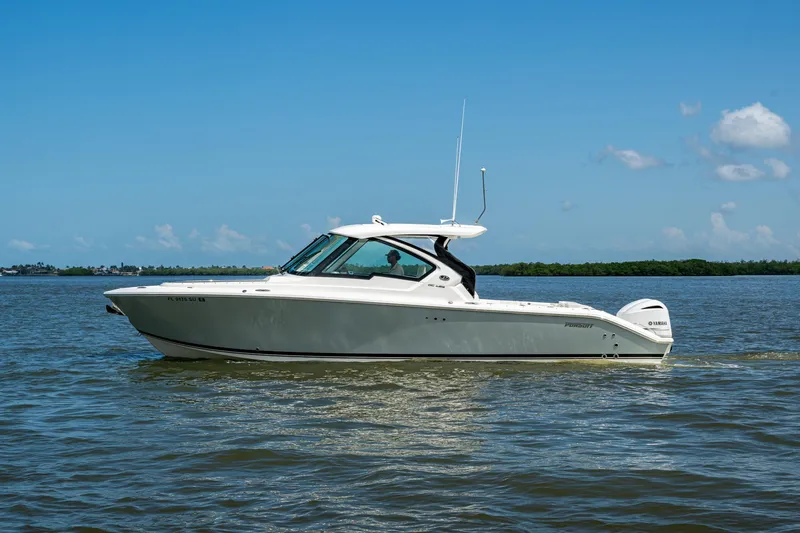  Yacht Photos Pics 2021 Pursuit DC 326 Dual Console boat cruising on calm waters under a clear blue sky.