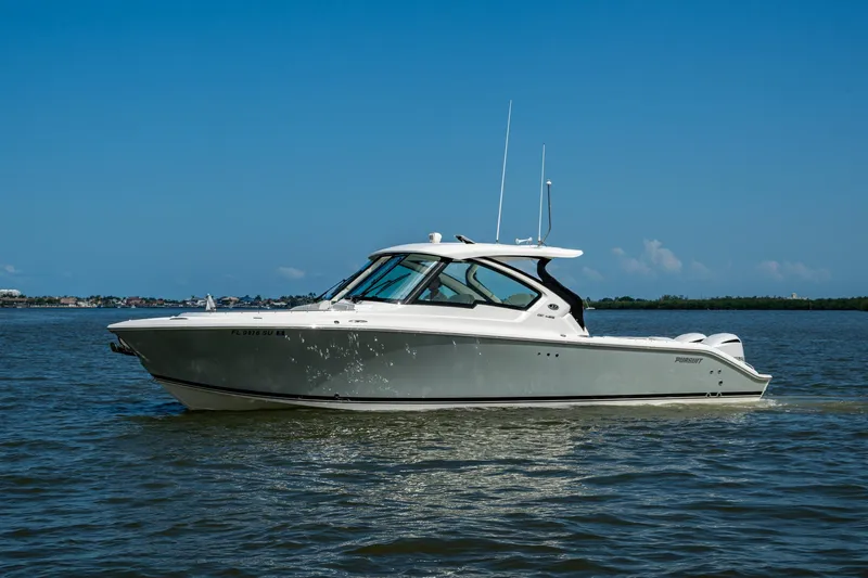  Yacht Photos Pics 2021 Pursuit DC 326 Dual Console boat cruising on calm waters under a clear blue sky.