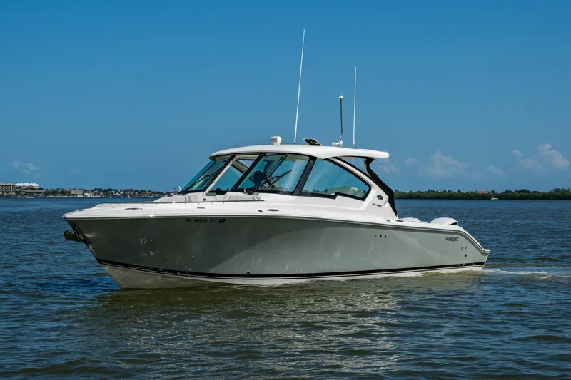 Yacht Photos Pics 2021 Pursuit DC 326 Dual Console boat cruising on calm waters under a clear blue sky.