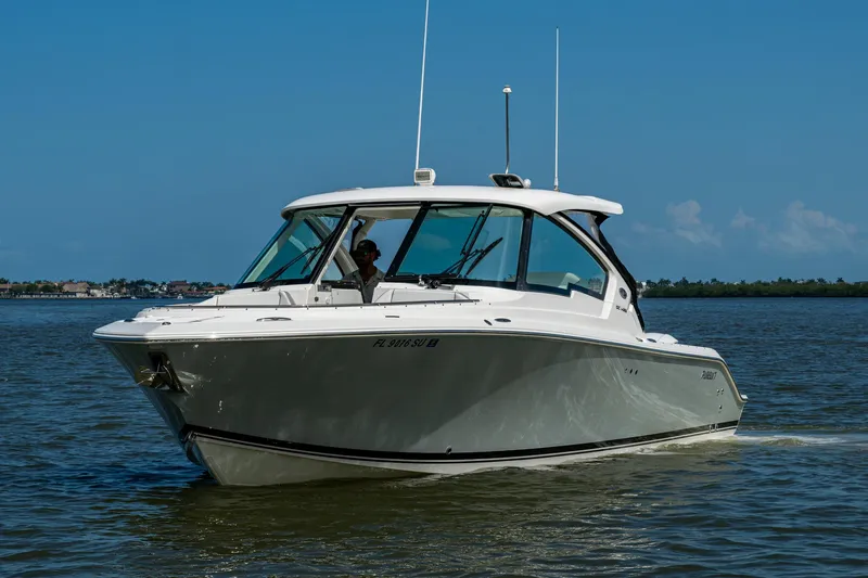  Yacht Photos Pics 2021 Pursuit DC 326 Dual Console boat cruising on calm waters under a clear blue sky.
