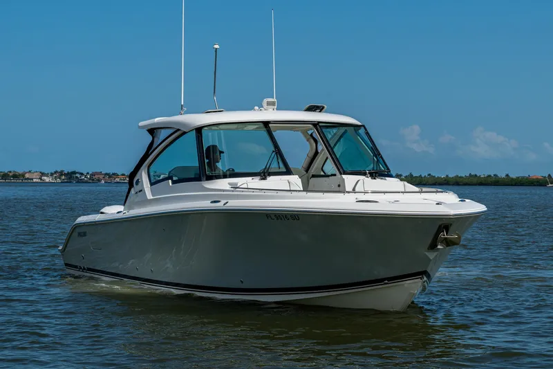  Yacht Photos Pics 2021 Pursuit DC 326 Dual Console boat cruising on calm waters under a clear blue sky.