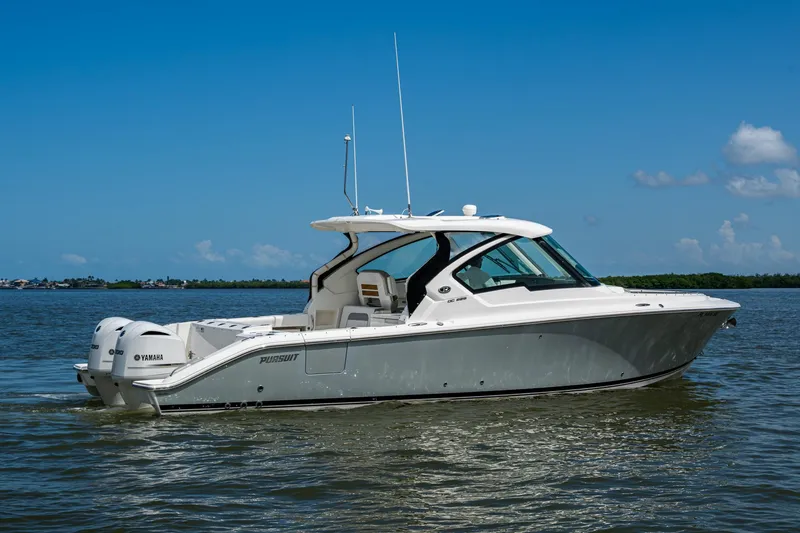  Yacht Photos Pics 2021 Pursuit DC 326 Dual Console boat cruising on calm waters under a clear blue sky.