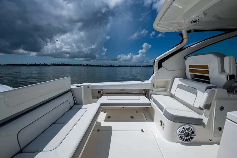  Yacht Photos Pics 2021 Pursuit DC 326 Dual Console boat interior with seating, overlooking calm waters and cloudy sky.