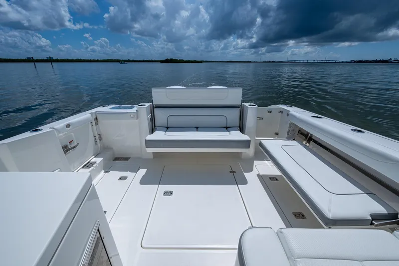  Yacht Photos Pics 2021 Pursuit DC 326 Dual Console boat interior with seating, on calm water under cloudy sky.