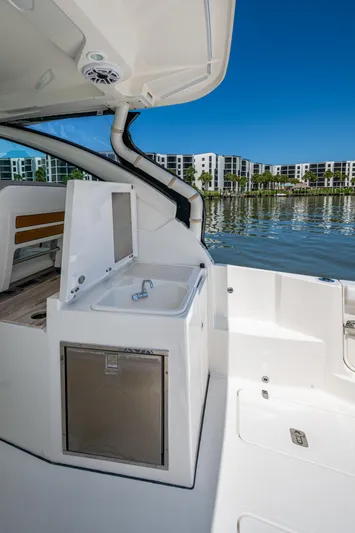  Yacht Photos Pics 2021 Pursuit DC 326 Dual Console boat with sink and storage, docked by waterfront buildings.