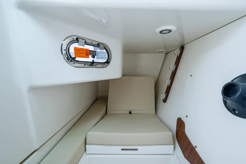  Yacht Photos Pics 2021 Pursuit DC 326 Dual Console cabin interior with cushioned seating and porthole.