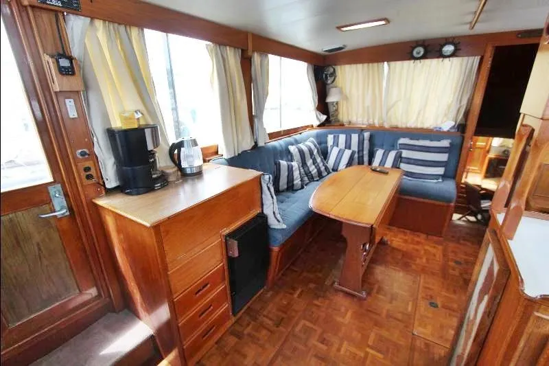  Yacht Photos Pics 1989 Grand Banks Classic yacht interior with wood furnishings, blue seating, and striped cushions.