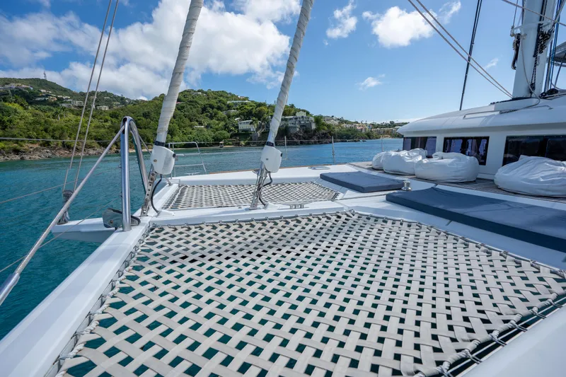  Yacht Photos Pics Lagoon 620 catamaran deck with netting, 2014 model, anchored in scenic coastal waters.