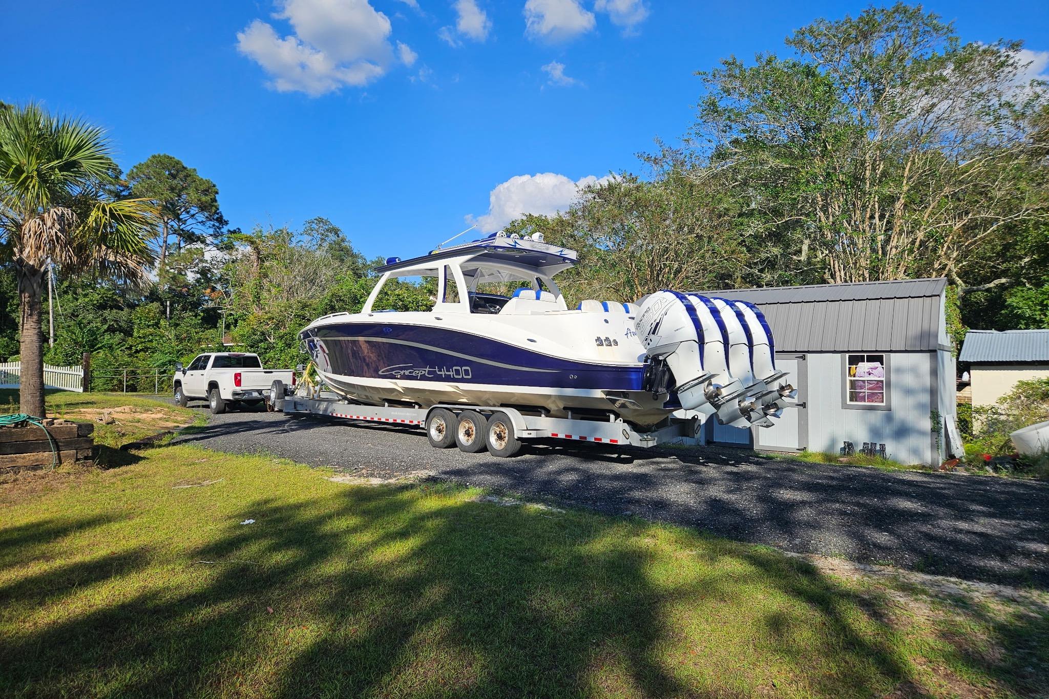 2019 Concept 44' Cuddy Cabin boat on trailer, parked near a house, sunny day.
