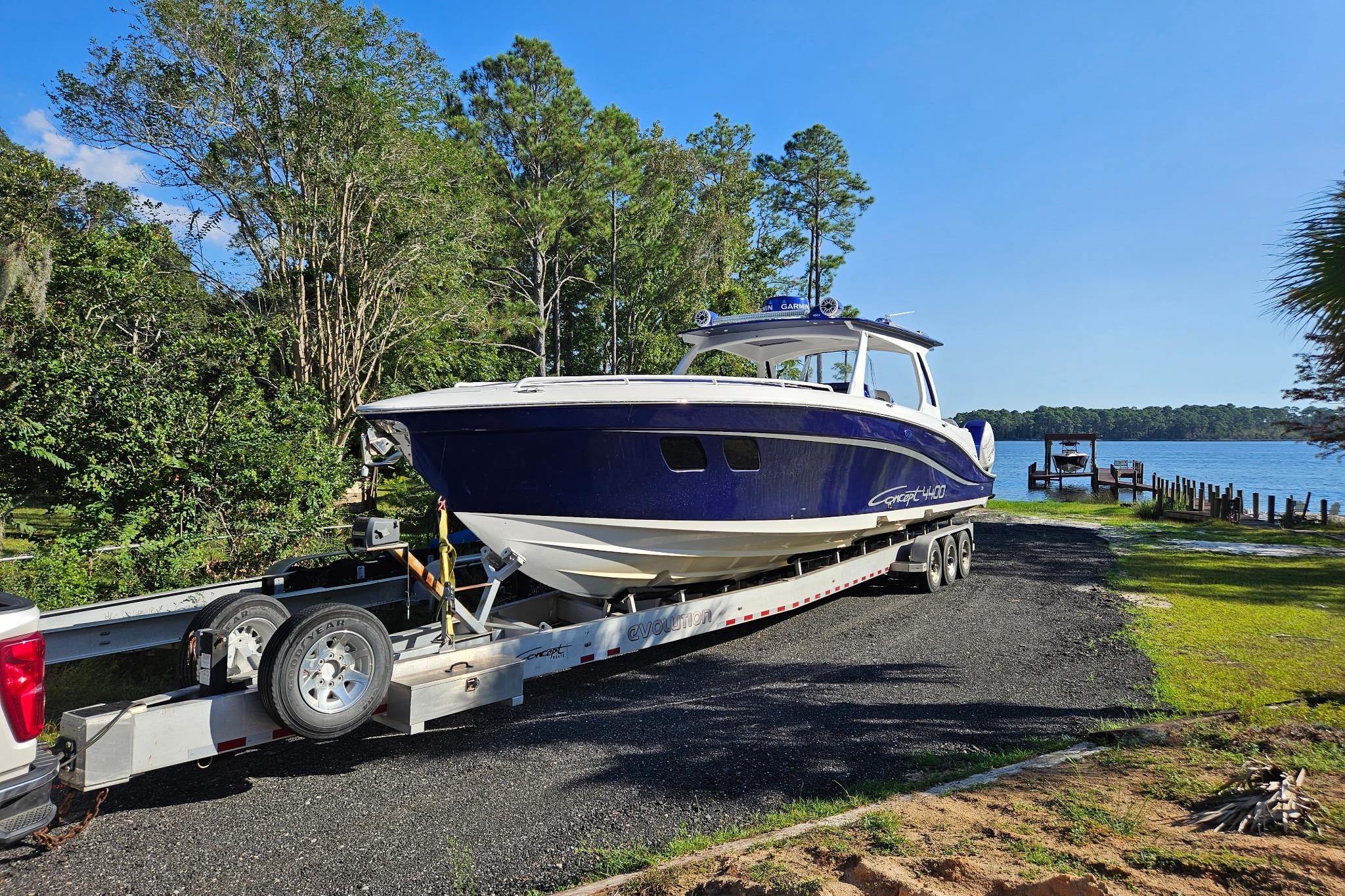 2019 Concept 44' Cuddy Cabin boat on trailer by lakeside, surrounded by trees.