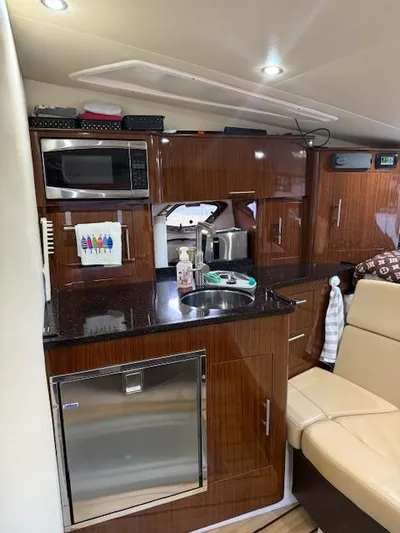  Yacht Photos Pics Compact kitchen in 2013 Regal 35 Sport Coupe with microwave, sink, and wooden cabinetry.