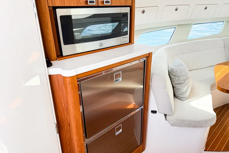  Yacht Photos Pics 2018 Intrepid 438 Evolution yacht interior with microwave, fridge, and seating area.