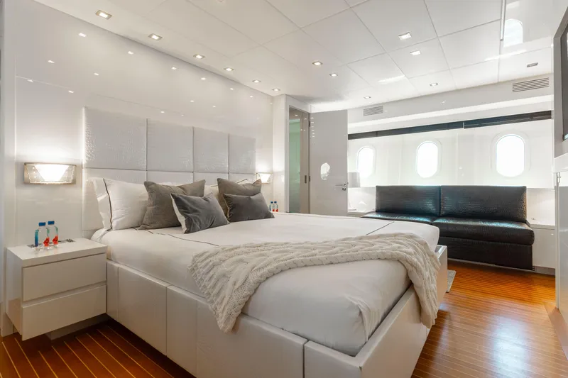 Venture Yacht Photos Pics Luxurious yacht bedroom with modern decor, featuring a large bed, sofa, and elegant lighting.