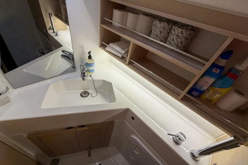 Coastal Distancing Yacht Photos Pics Bathroom sink area in a 2021 Beneteau Oceanis 30.1 yacht, featuring storage shelves.