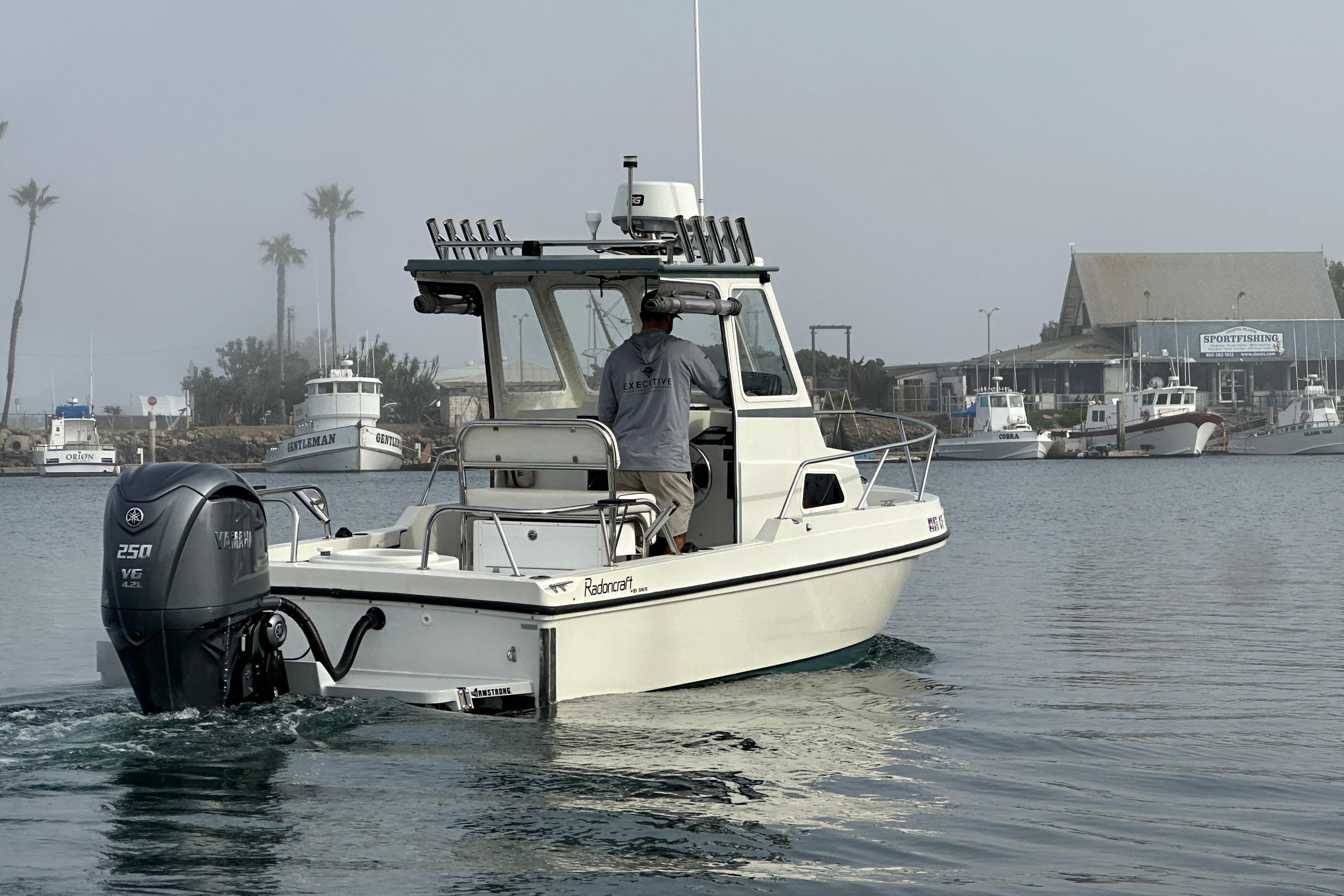 1993 Davis Radoncraft boat navigating a calm harbor with palm trees and buildings in the background.