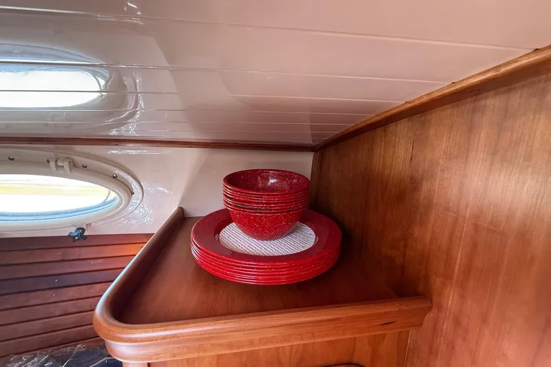 Timothy E Yacht Photos Pics Red dishware set on wooden shelf inside 2001 Hinckley Classic Picnic Boat cabin.