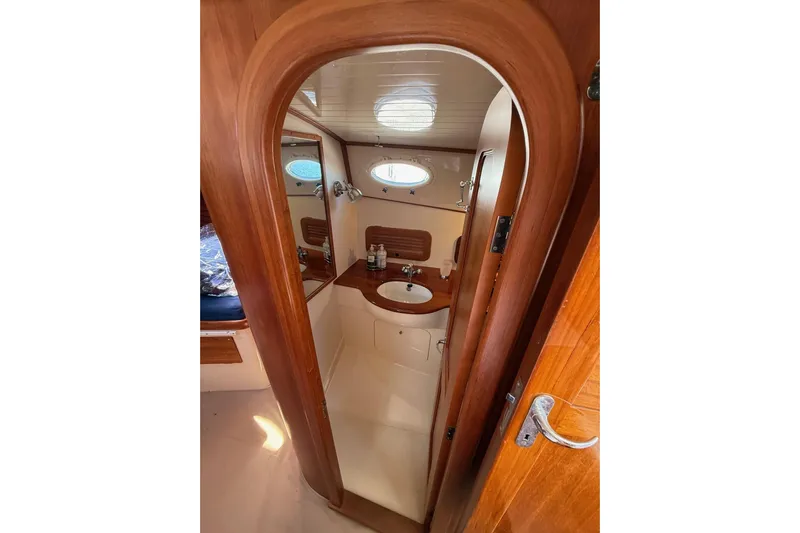 Timothy E Yacht Photos Pics Interior of 2001 Hinckley Classic Picnic Boat bathroom with wooden finish and porthole window.