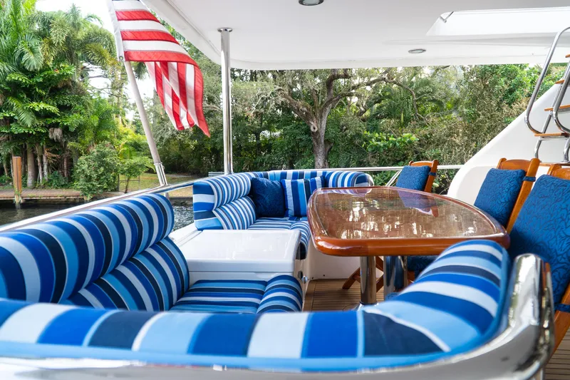 Jusmad Yacht Photos Pics Luxurious seating area on 2005 Ocean Alexander 80 yacht with striped cushions and wooden table.