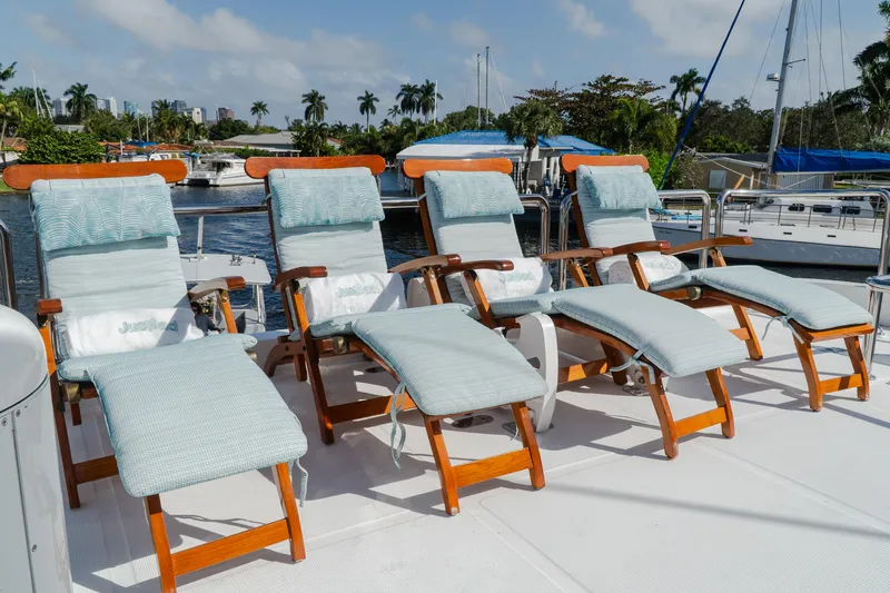 Jusmad Yacht Photos Pics Deck chairs on 2005 Ocean Alexander 80 yacht, docked by palm trees and water.