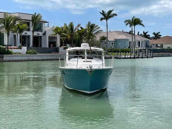  Yacht Photos Pics 2023 MJM 35z boat cruising in a serene canal near luxury waterfront homes.
